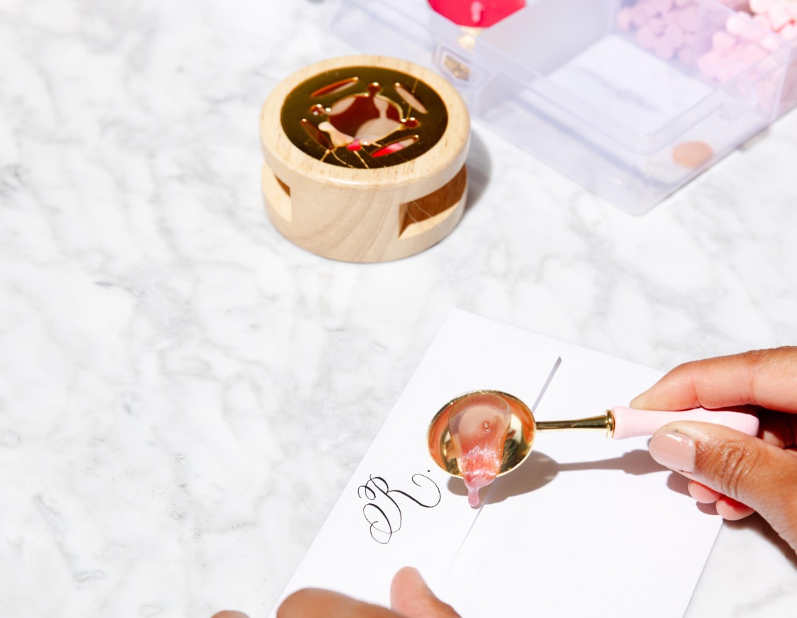 Live calligraphy — pouring a wax seal onto a hand-lettered envelope